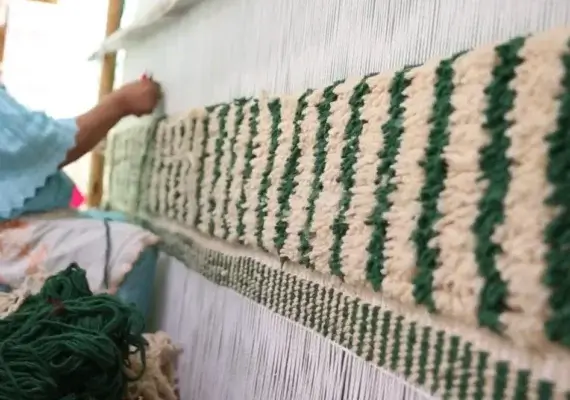 Marokkanische Kunsthandwerkerin knüpft einen Berber Teppich im Atlasgebirge.